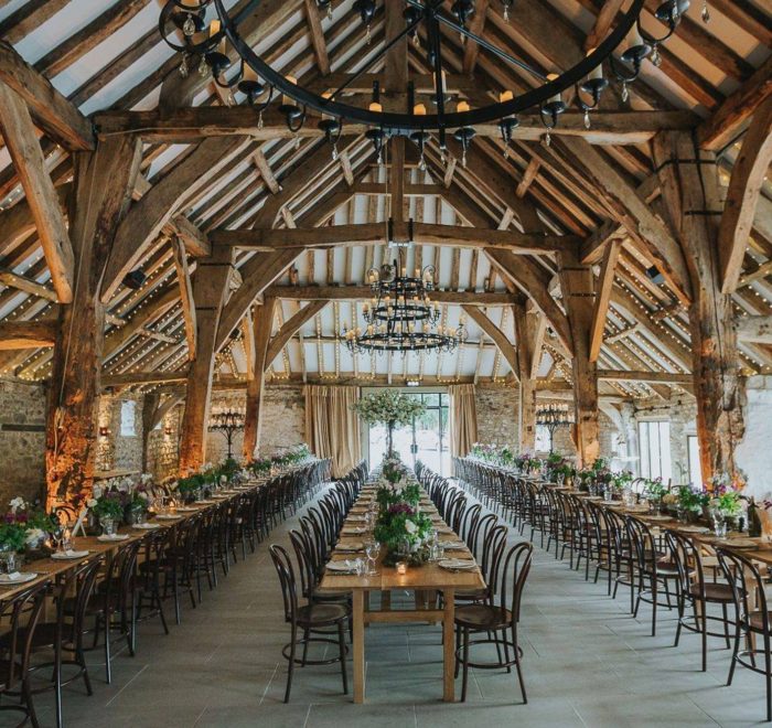 Exposed oak beamed building filled with dining tables and chairs for wedding reception