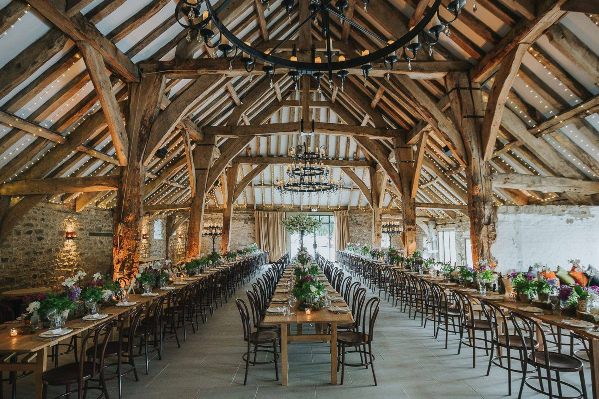 Exposed oak beamed building filled with dining tables and chairs for wedding reception