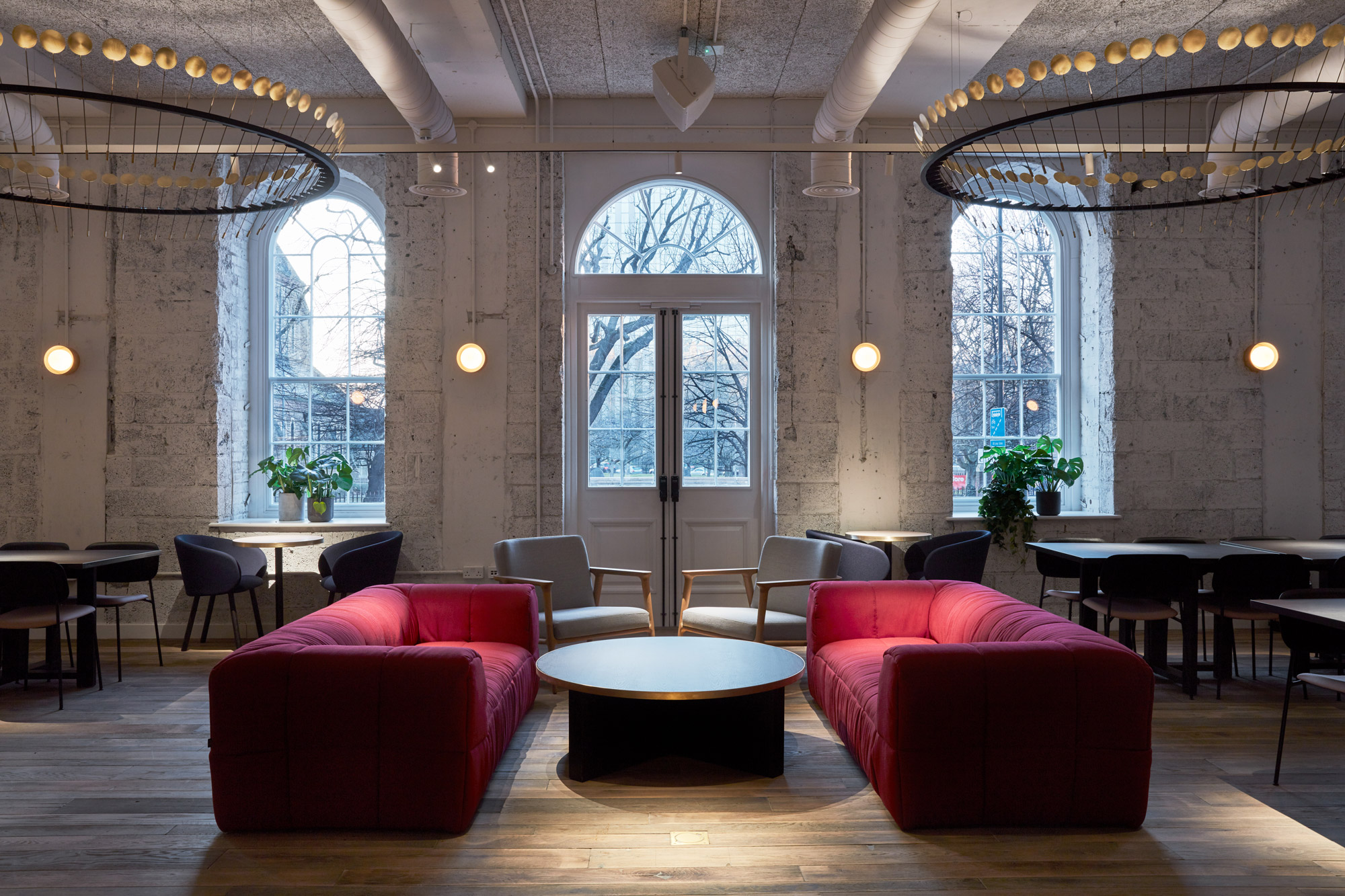 Two red sofas face each other with round coffee table in between and oak floorboards