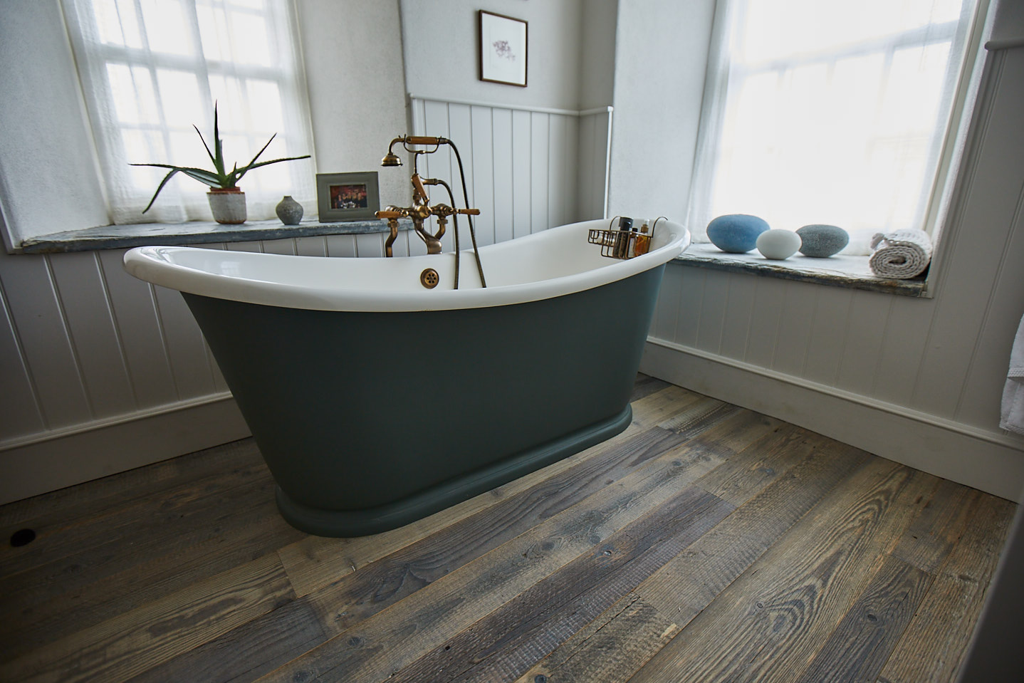 Freestanding roll top bath sits on reclaimed pine flooring