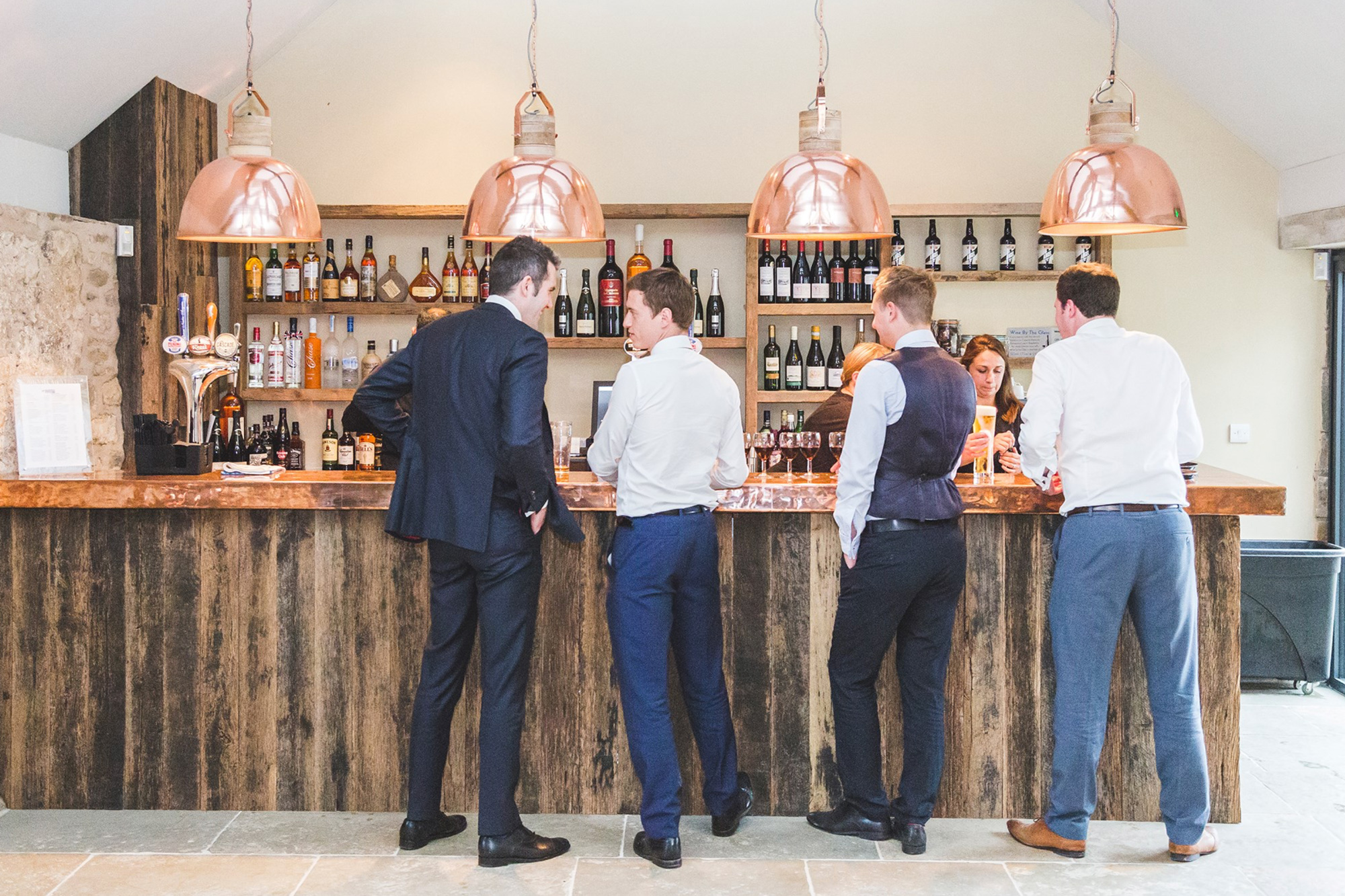 Men stood talking at bar with large pendant copper lights