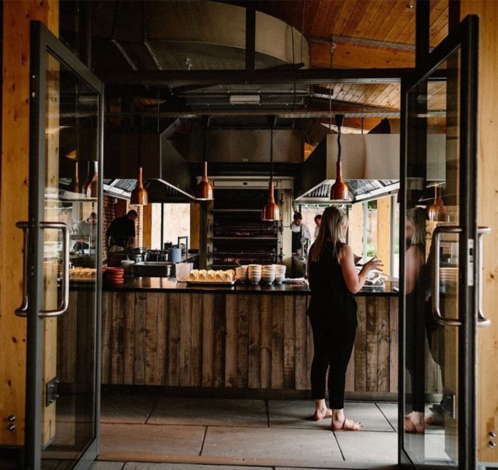 Lady stood at reclaimed wood piza bar with chef in background