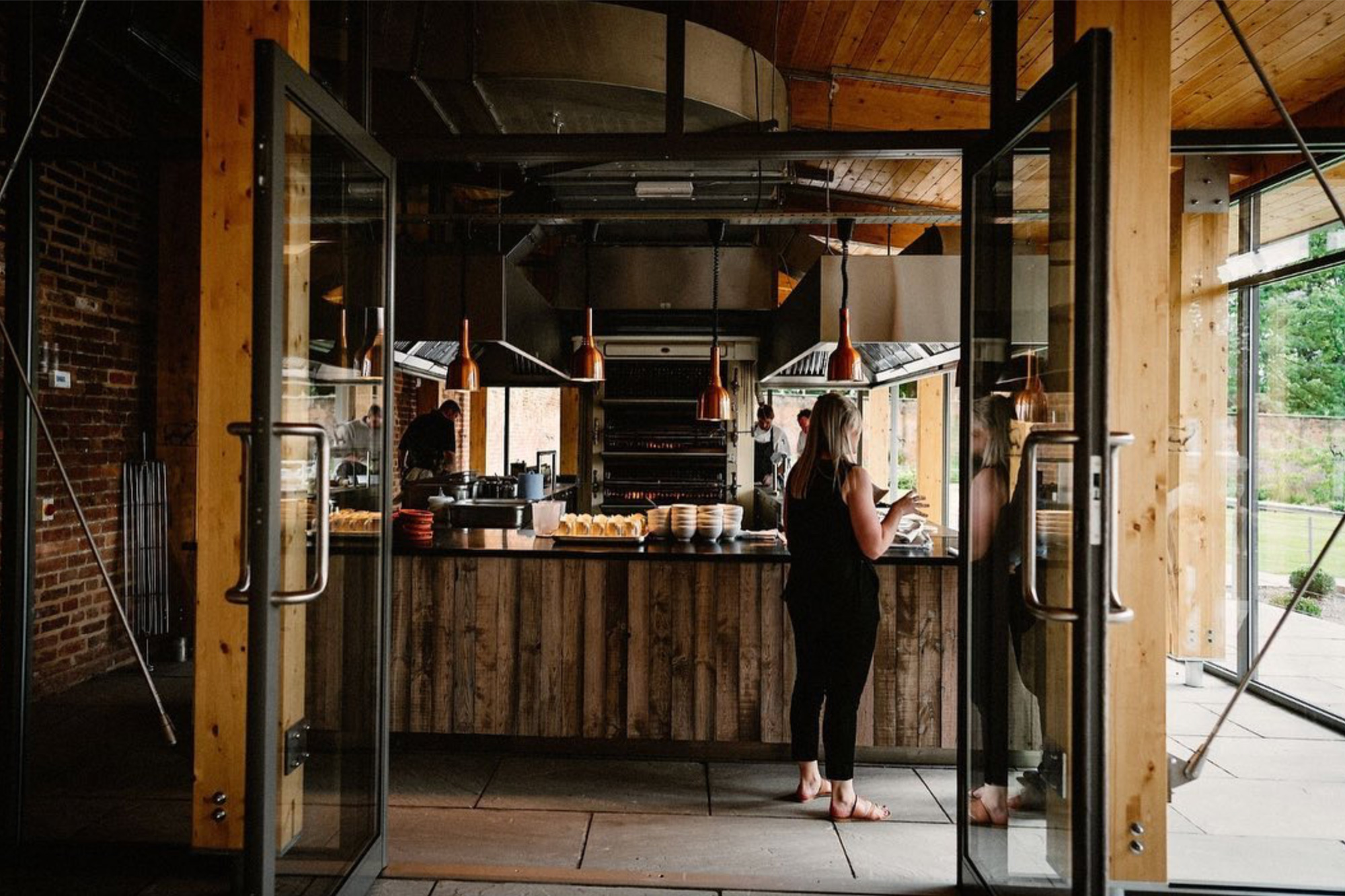 Lady stood at reclaimed wood piza bar with chef in background