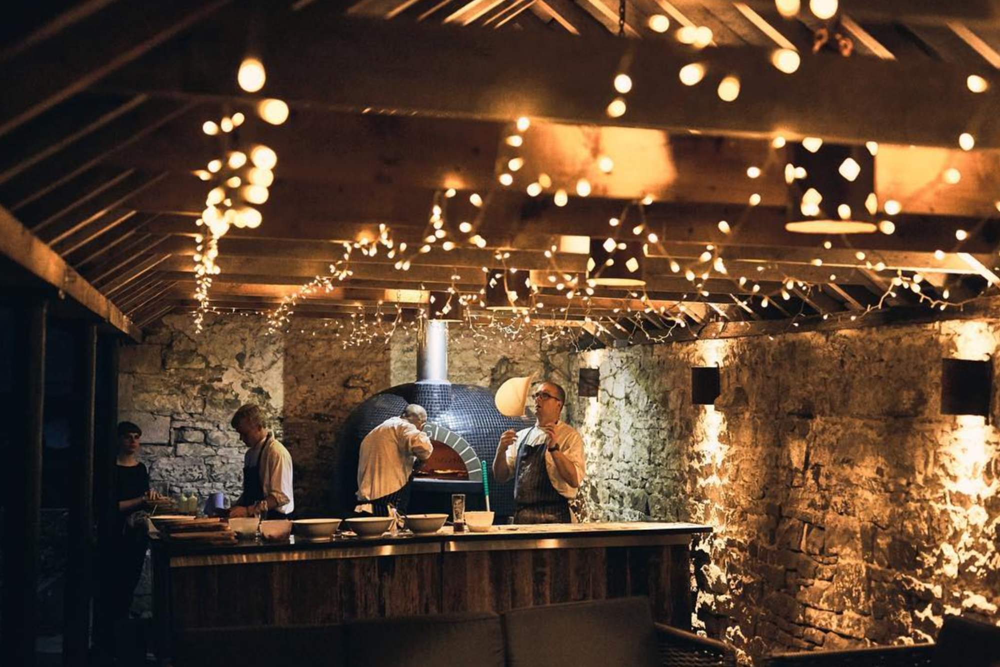 Chefs throwing pizza dough with open fire oven