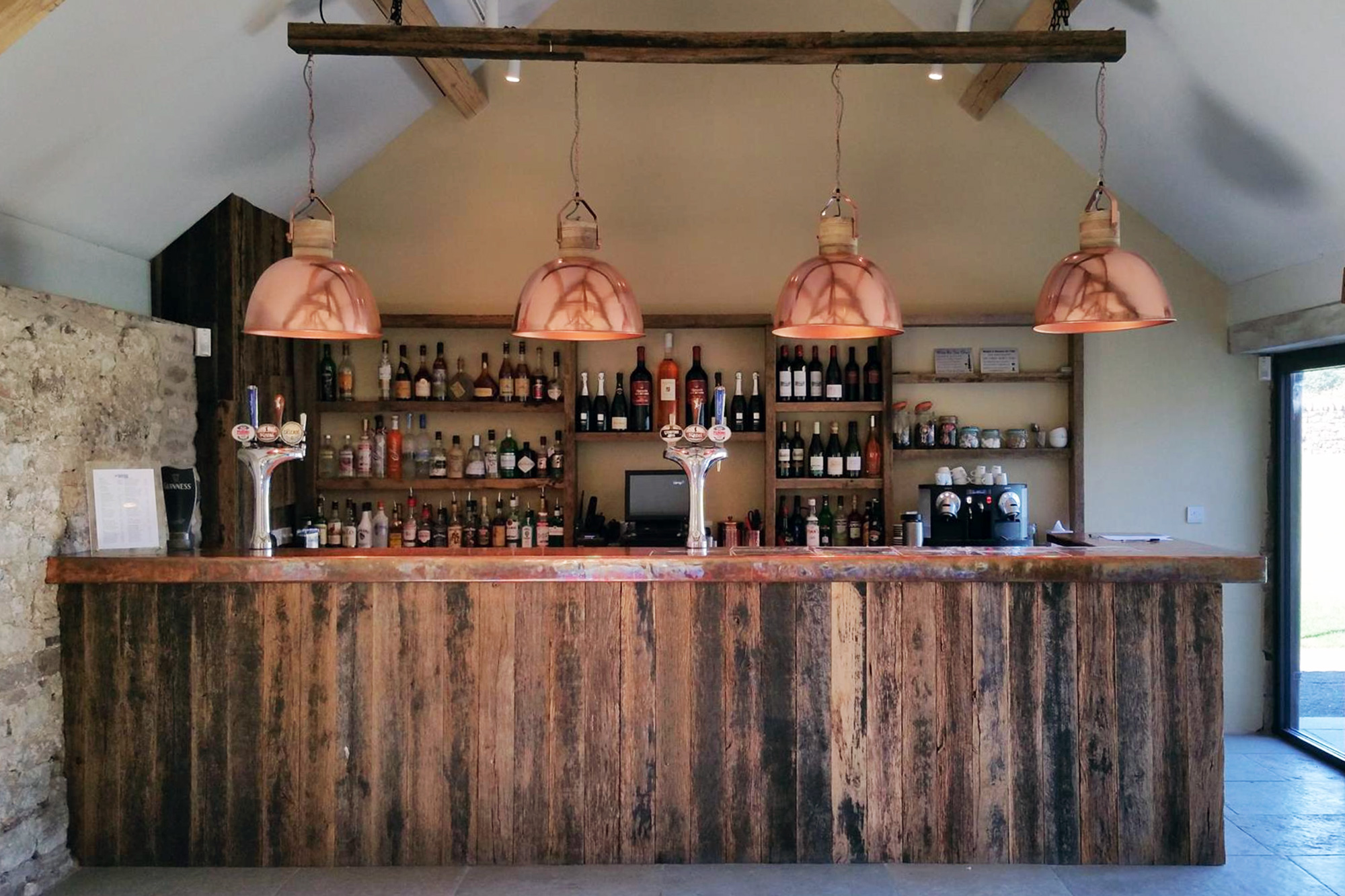 Reclaimed wood bar with large copper pendant lights above