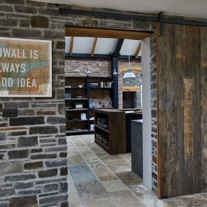 Reclaimed internal sliding barn door against stone wall