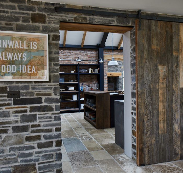 Reclaimed internal sliding barn door against stone wall