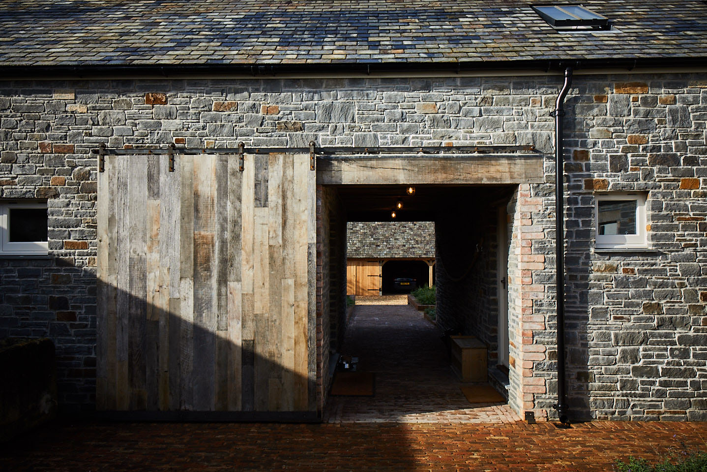 External sliding door mounted on stone barn with raw iron rail