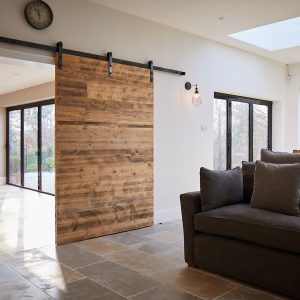 Internal sliding pine door open next to grey sofa with cushions