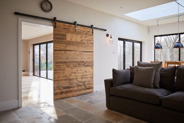 Internal sliding pine door open next to grey sofa with cushions