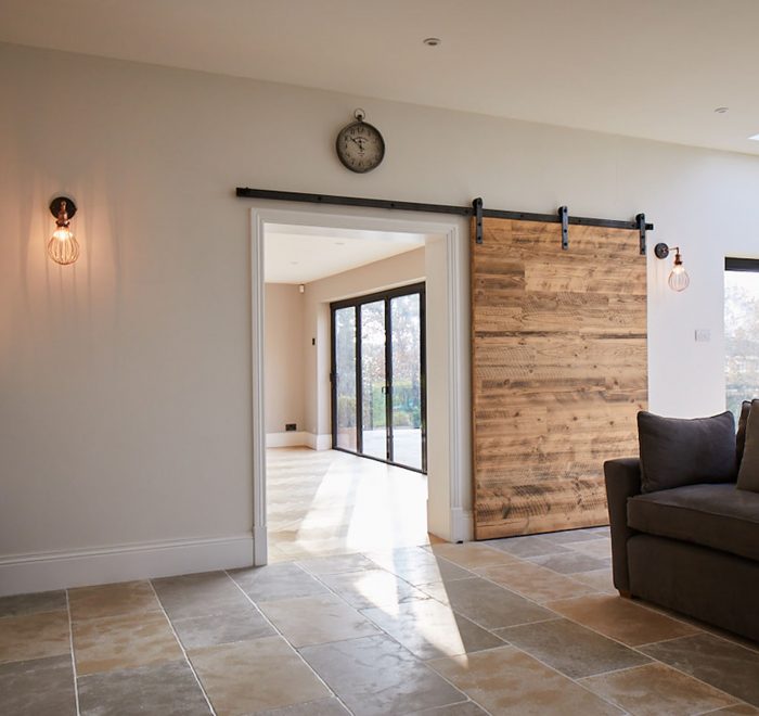 Internal sliding door with raw steel rail next to floor lamp and grey sofa