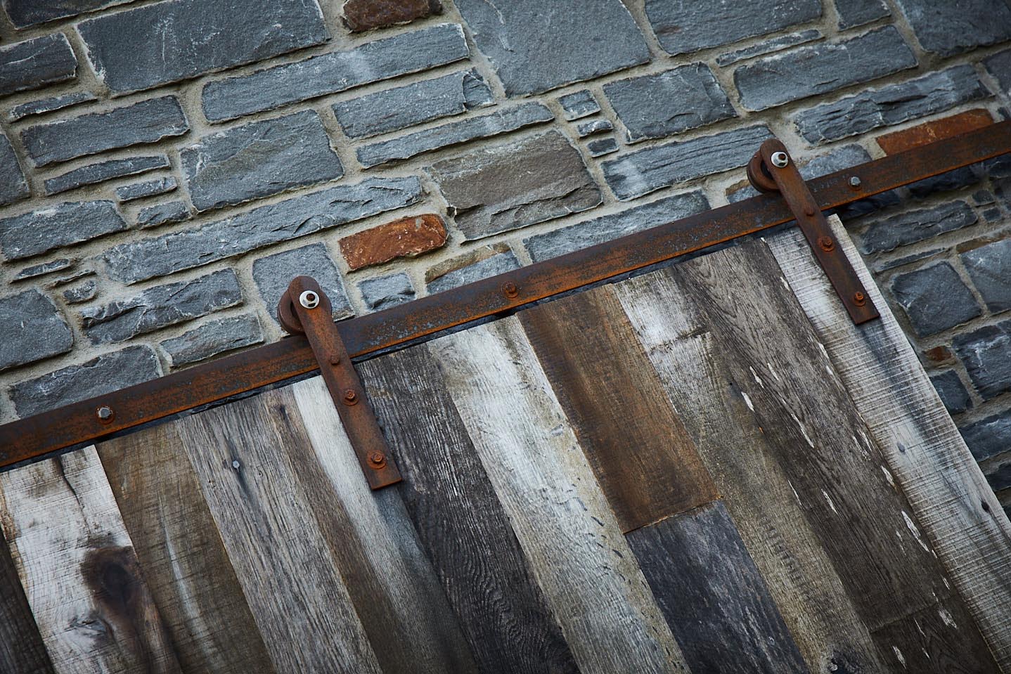Rusted raw steel sliding door mechanism against stone wall