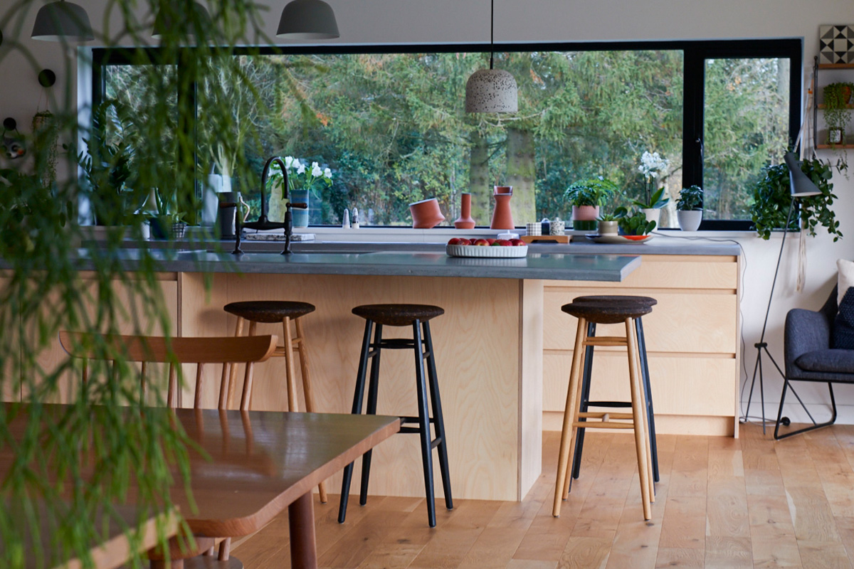 Dining table and oak barstools sit next to custom birch plywood kitchen