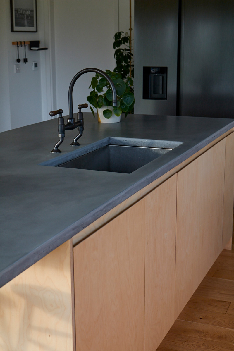 Solid grey concrete worktops on birch plywood sink unit