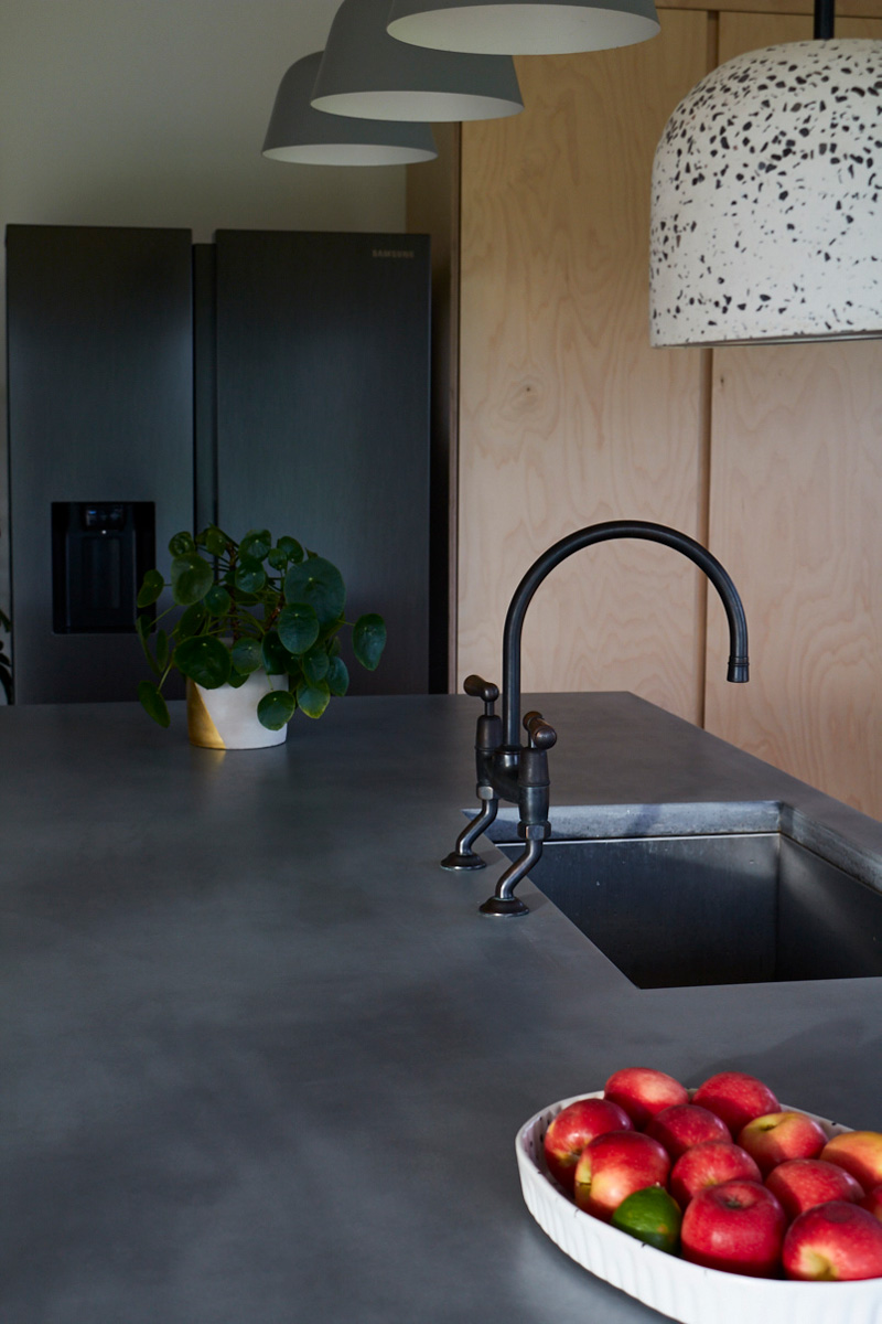 Solid grey concrete worktops with inbuilt sink and antique brass taps
