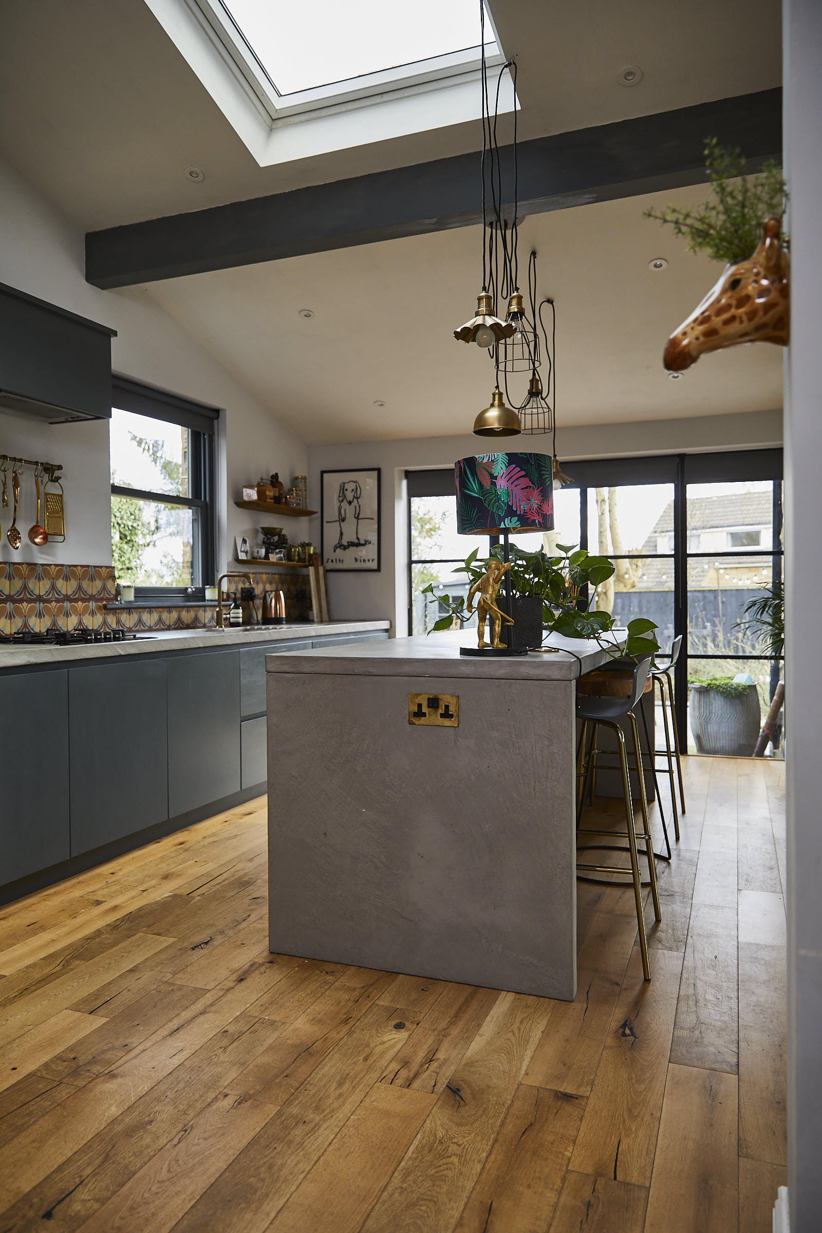 Solid concrete grey kitchen island with pendant lights above with geometric metal shades