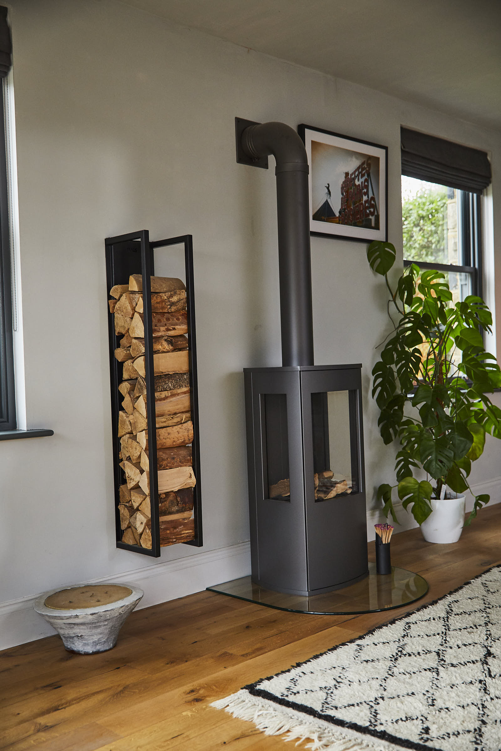 Black log burner with open log storage attached against wall