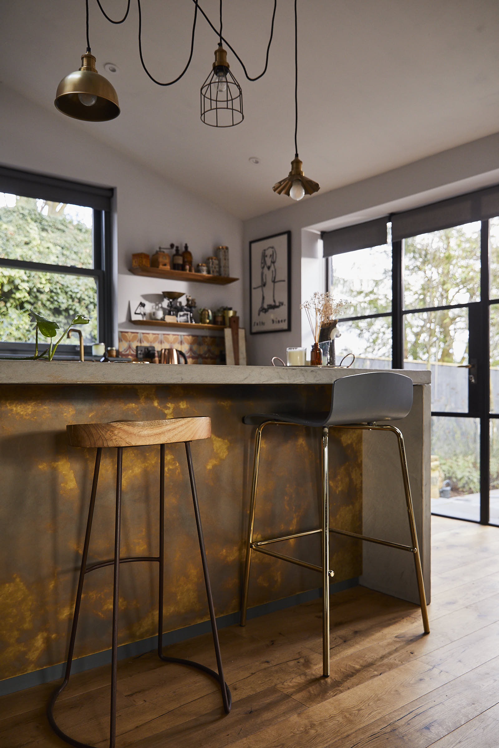 Oak and metal bar stool under solid grey concrete breakfast bar with antique brass back panel