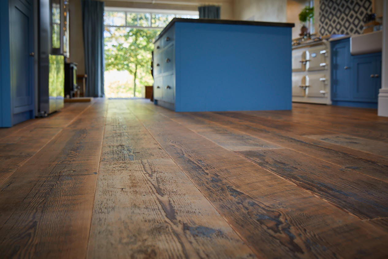 Brown rustic flooring with blue kitchen