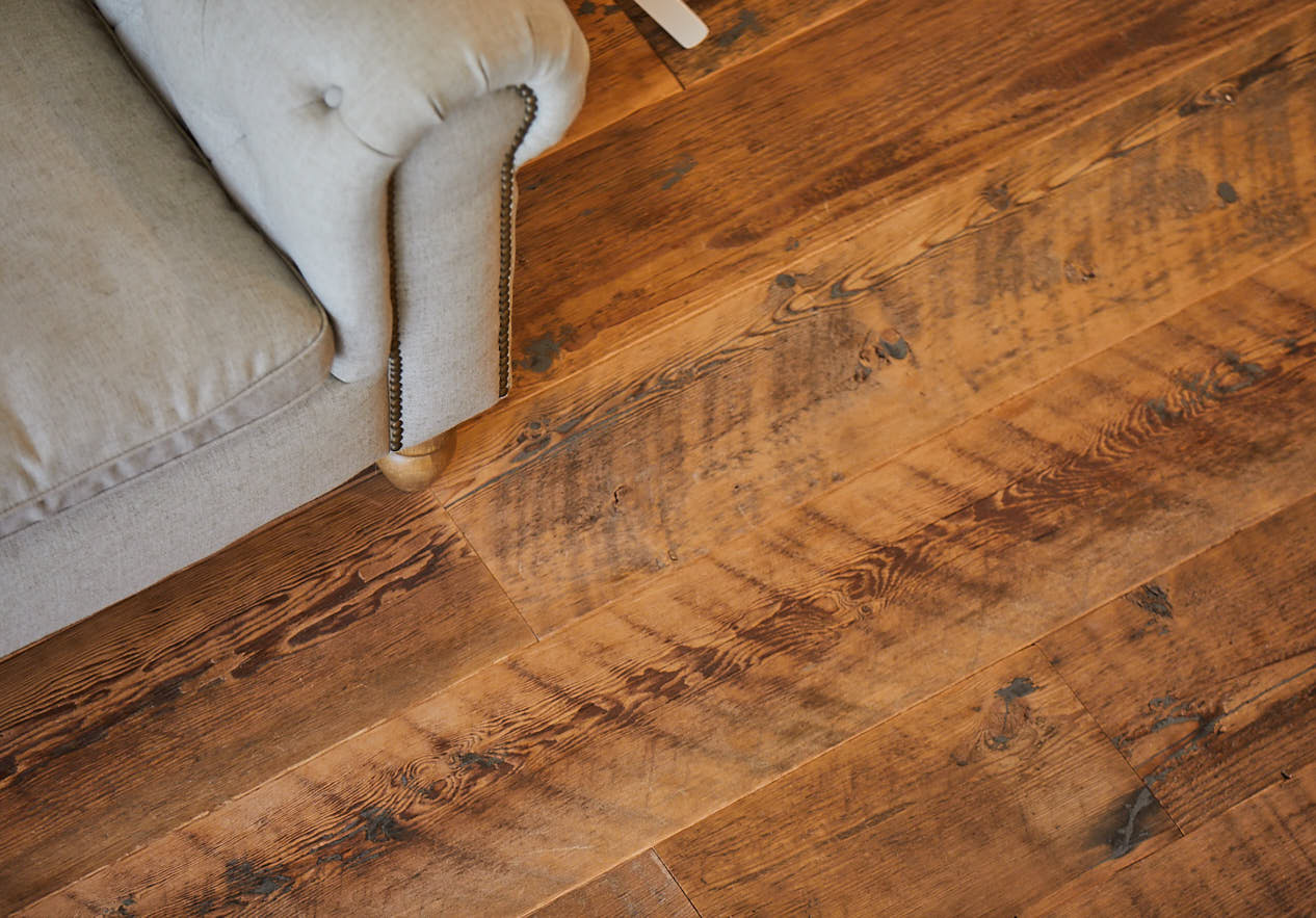 Reclaimed rustic flooring sits under upholstered sofa