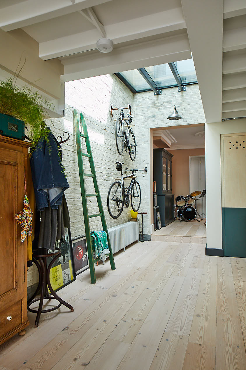 Green ladder and bikes stored against painted white wall