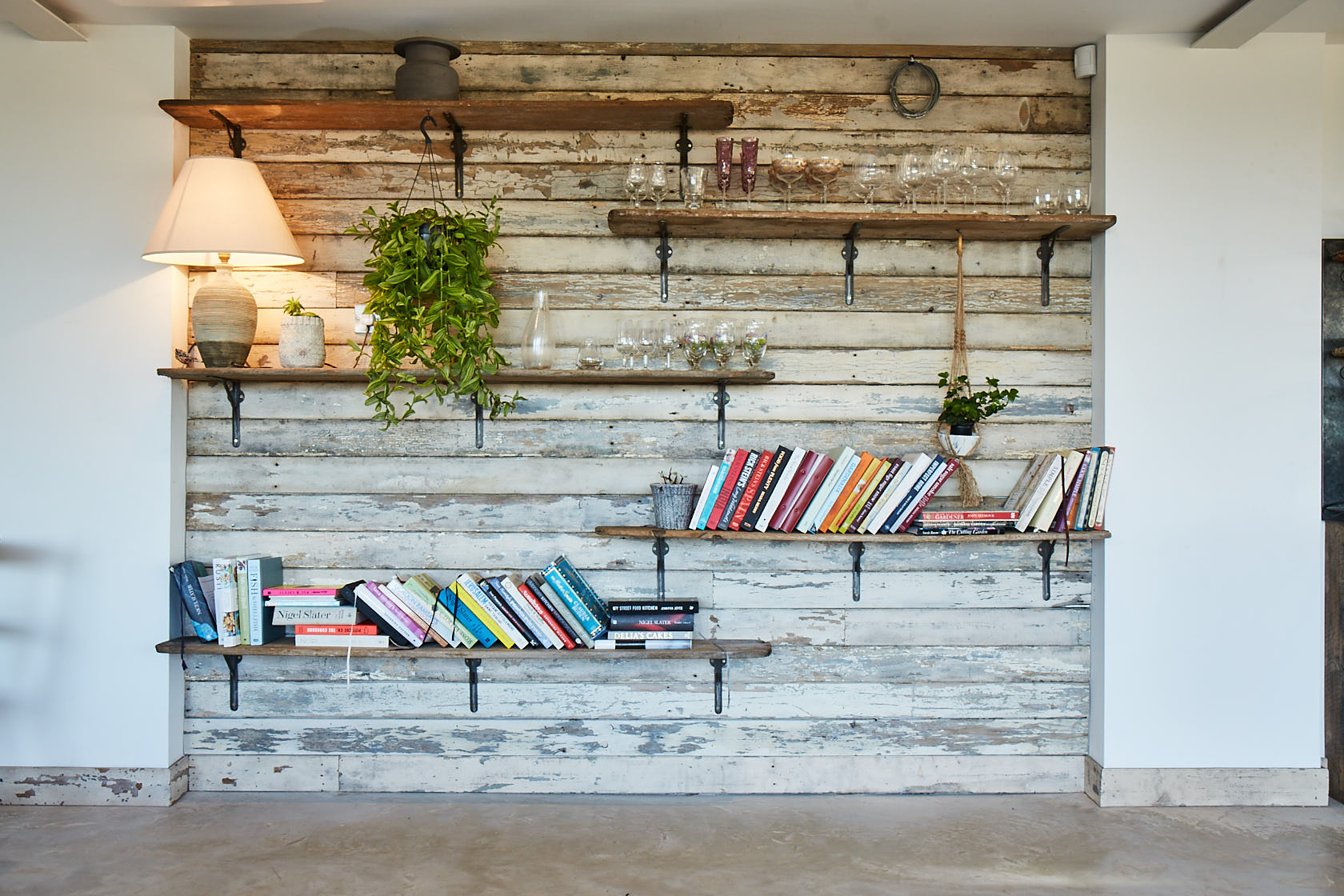 Cladded white wall with open rustic shelves on cast brackets