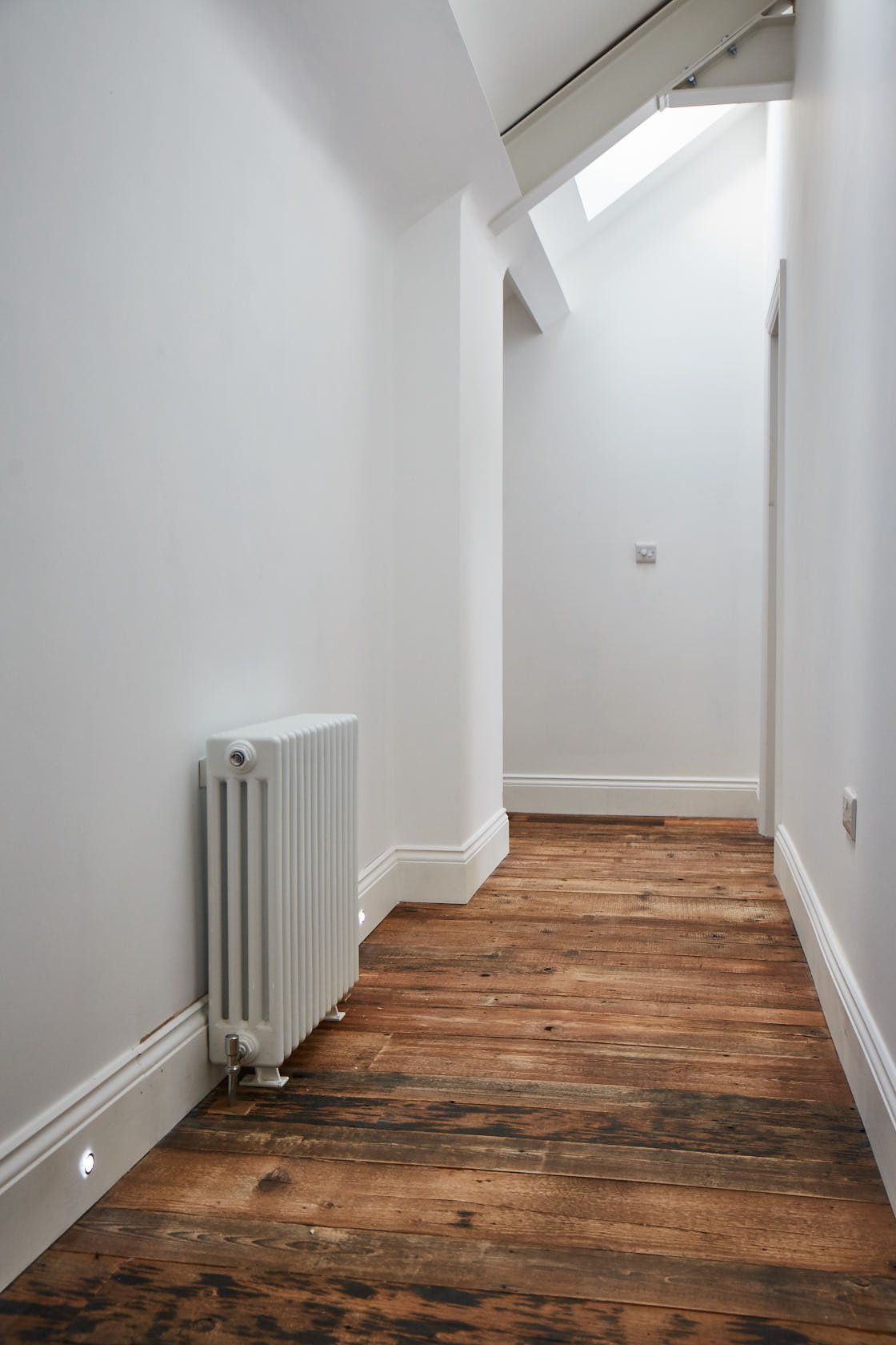 Brown barn board reclaimed flooring in white hallway