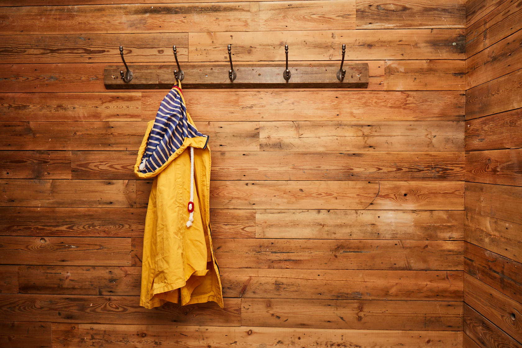 Bright yellow coat against reclaimed pine wall cladding