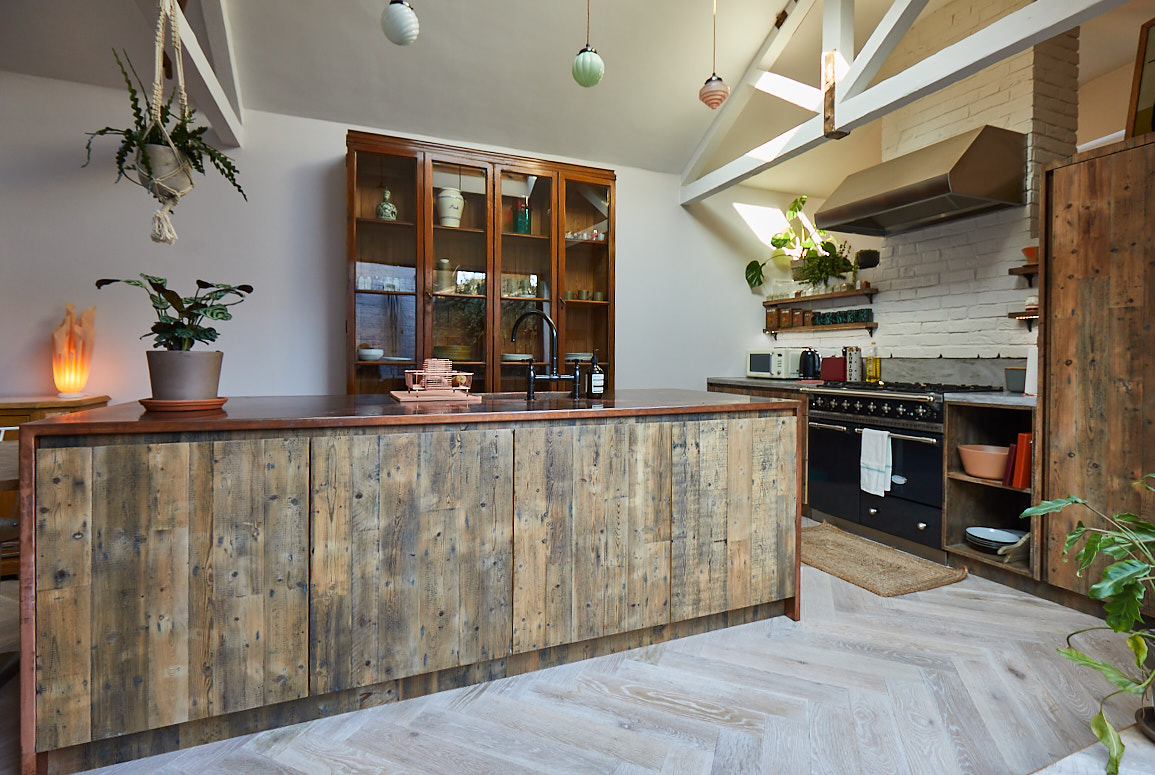 Integrated dishwasher in bespoke kitchen island with reclaimed pine units and copper worktop