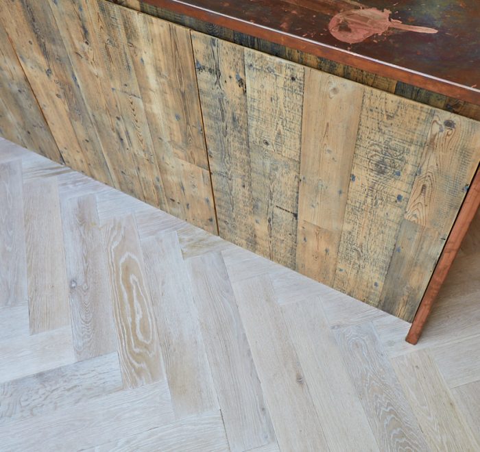 Reclaimed pine kitchen unit sit on whitewash oak parquet flooring