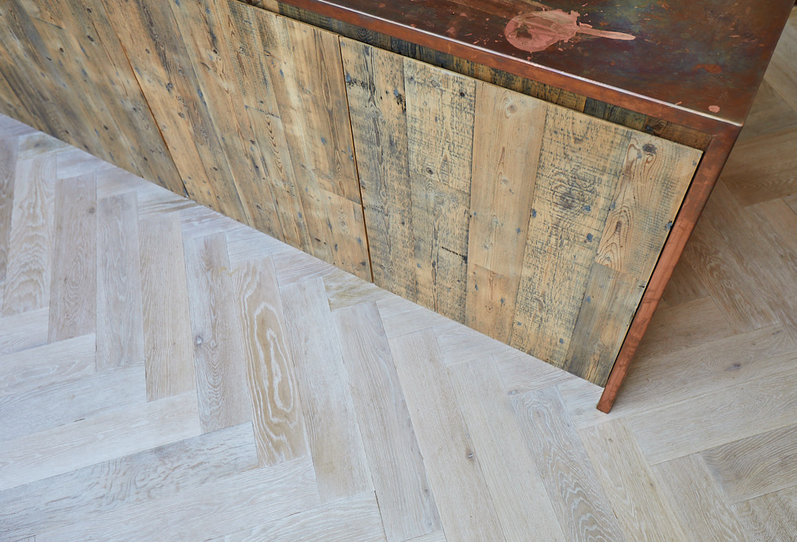 Reclaimed pine kitchen unit sit on whitewash oak parquet flooring