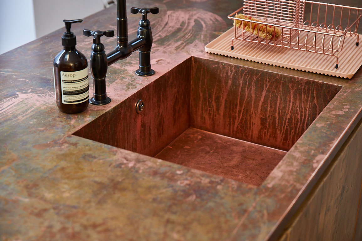 Seamless copper kitchen worktop with integrated sink and black tap