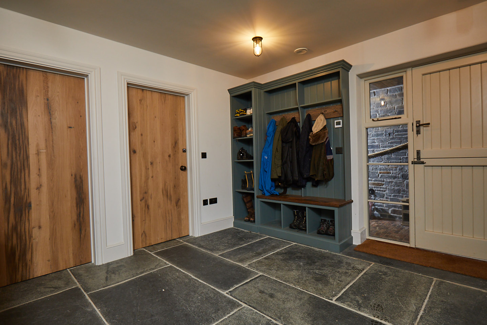 Green boot cupboard with integrated rustic seat and clothes hanger