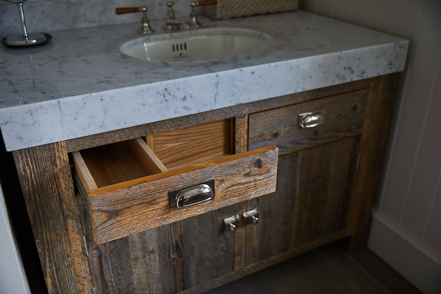 Rustic vanity drawer is shaped around pipes