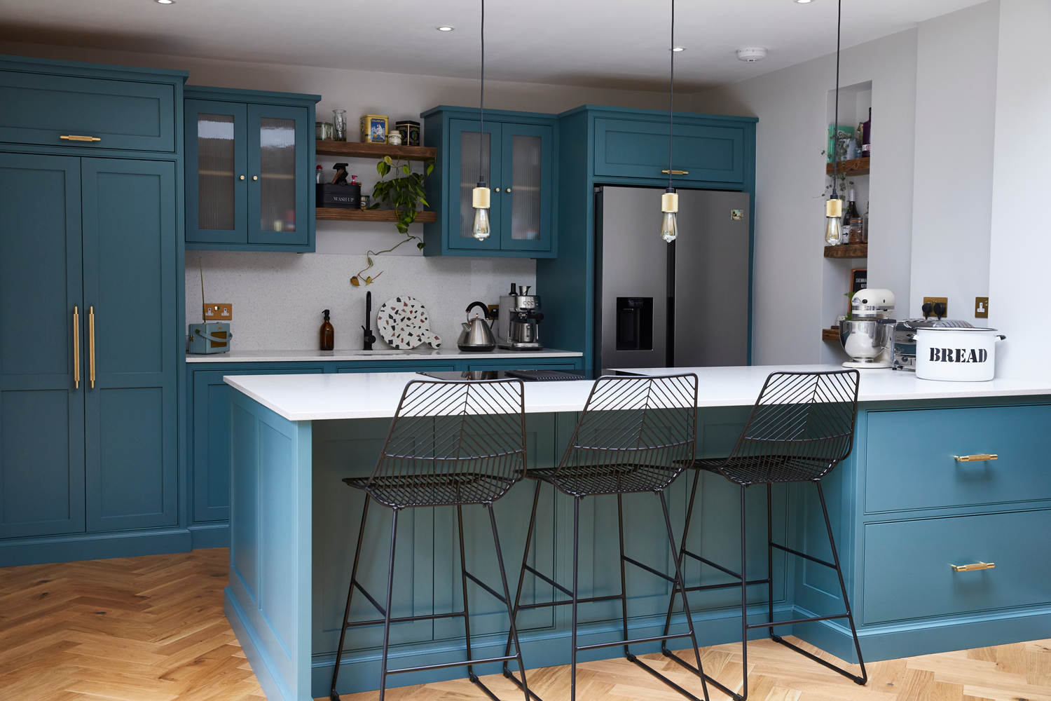 Bespoke blue green kitchen with black metal bar stools finished with brass buster + punch hardware