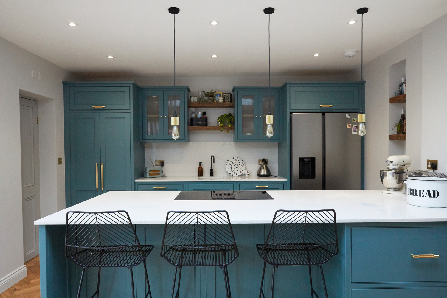 Bespoke kitchen peninsular with black metal barstools and buster + Punch brass bar handles