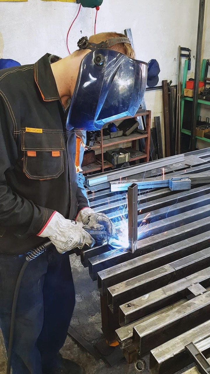 Worker welding hinges on to stock metal doors