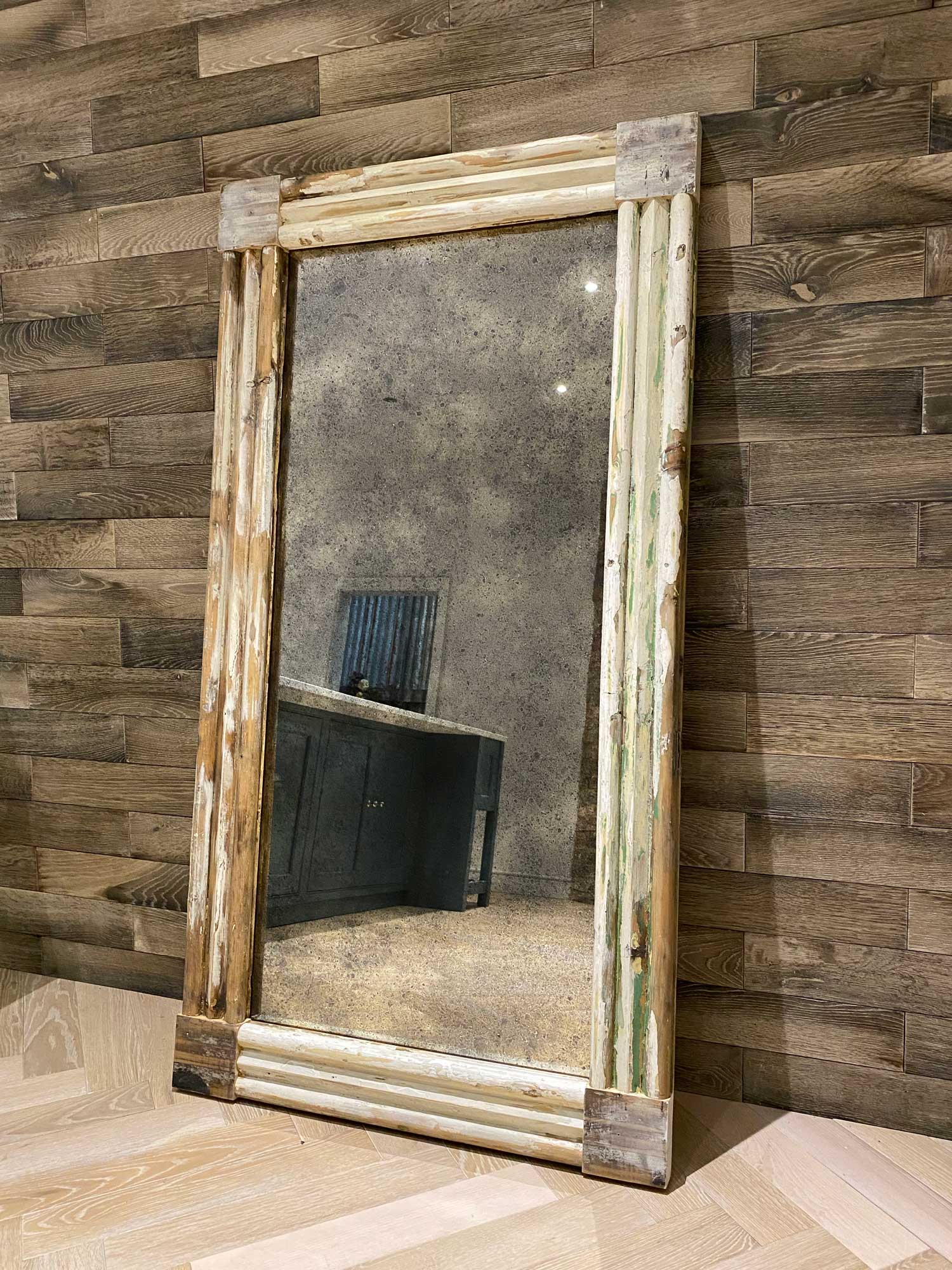 Large Antique mirror with reclaimed frame against parquet wall