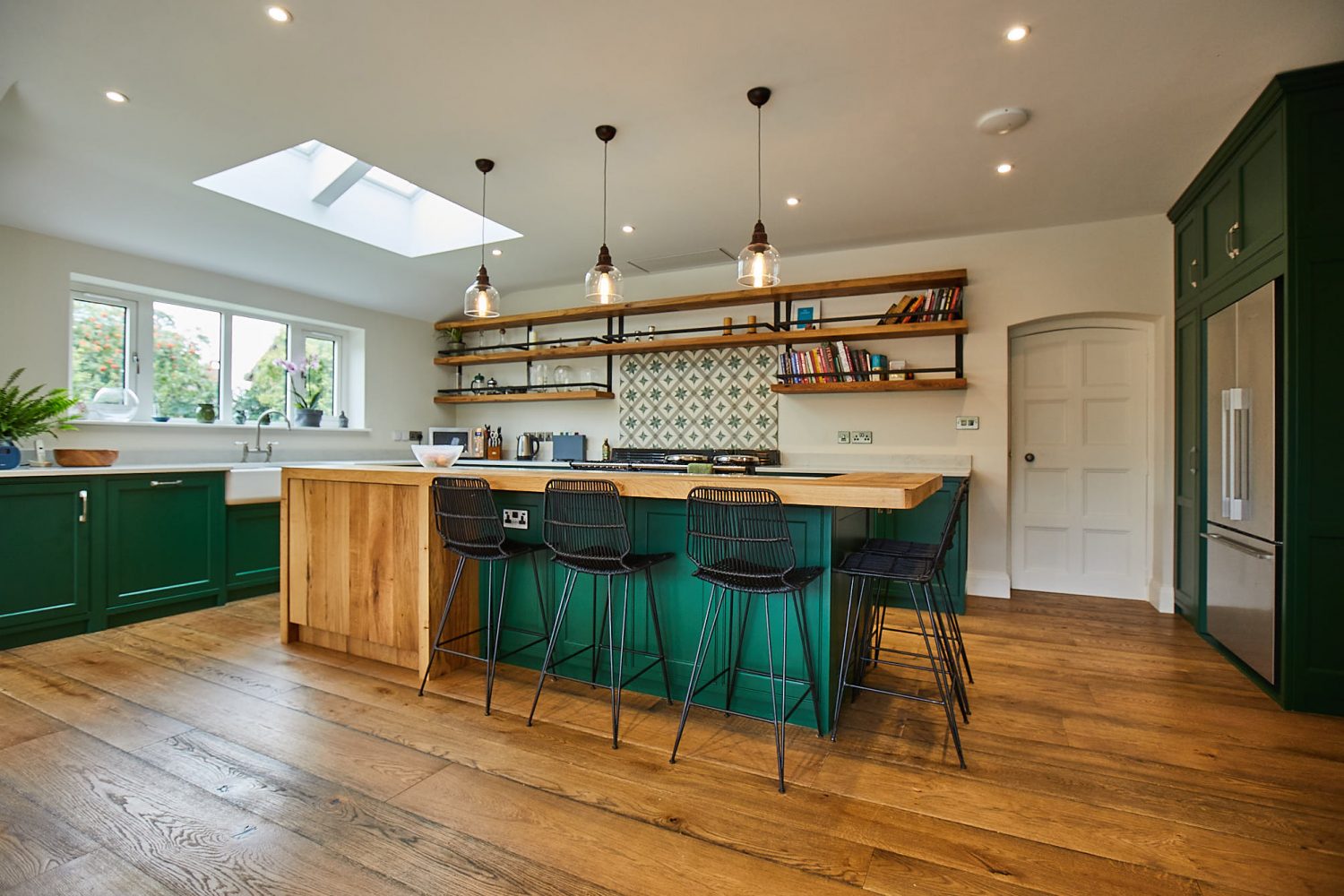 Bepoke kitchen island with clean oak cabinets contrasting with green painted cabinets