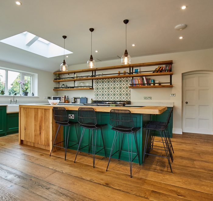 Bepoke kitchen island with clean oak cabinets contrasting with green painted cabinets