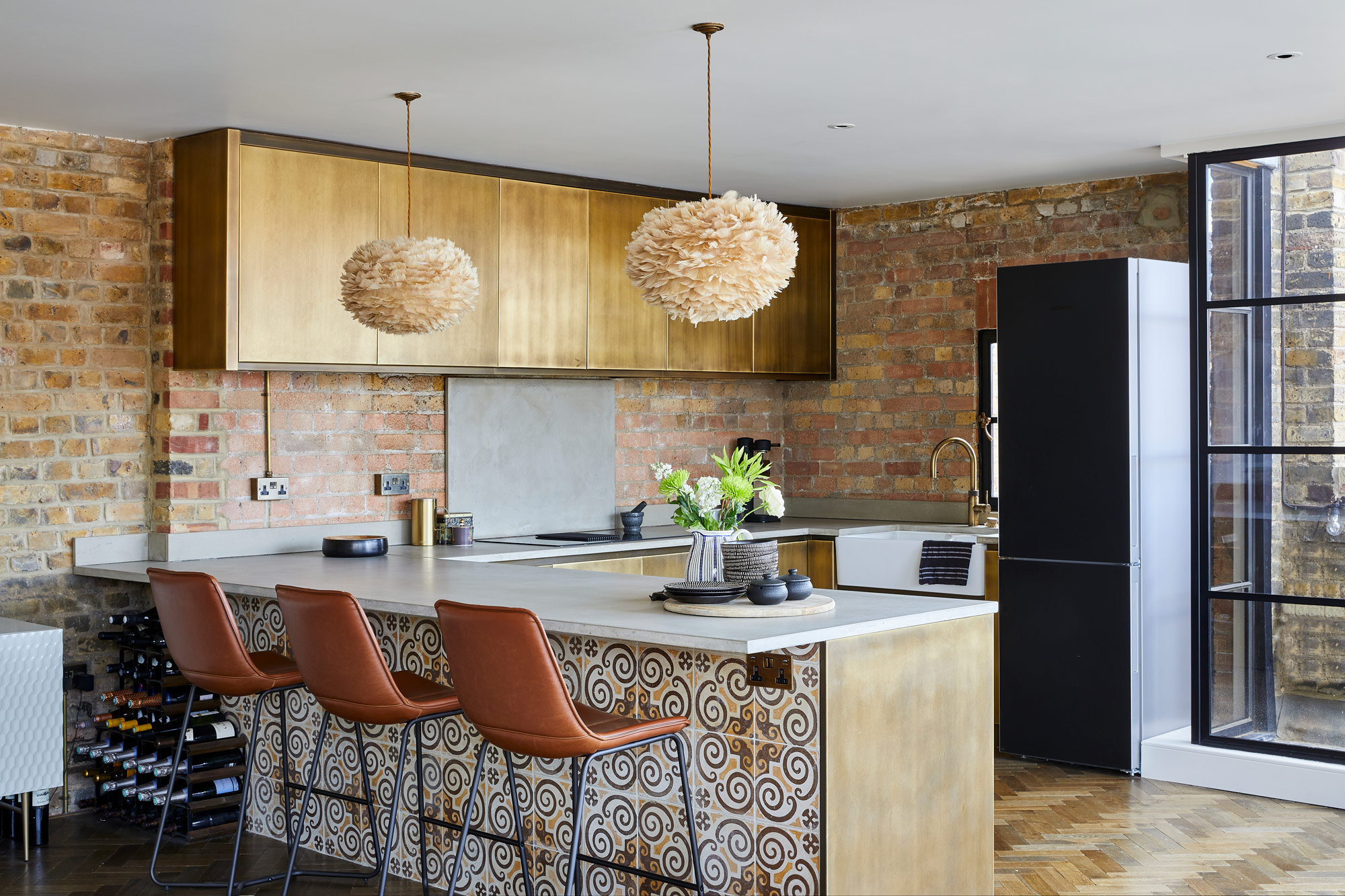 Brass metal kitchen with tiled peninsular and concrete worktops