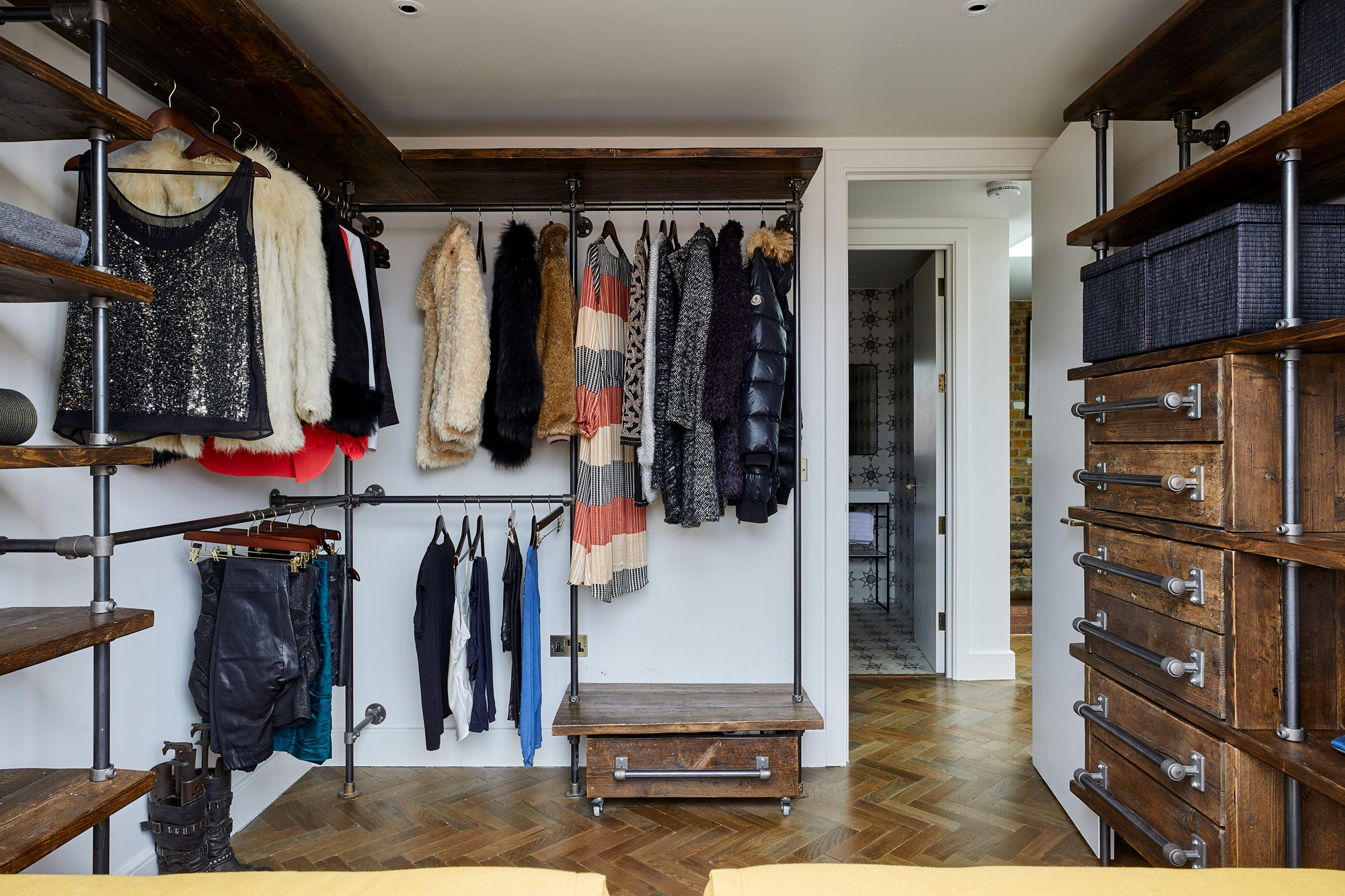 Open plan walk in wardrobe with rustic shelves and pipework