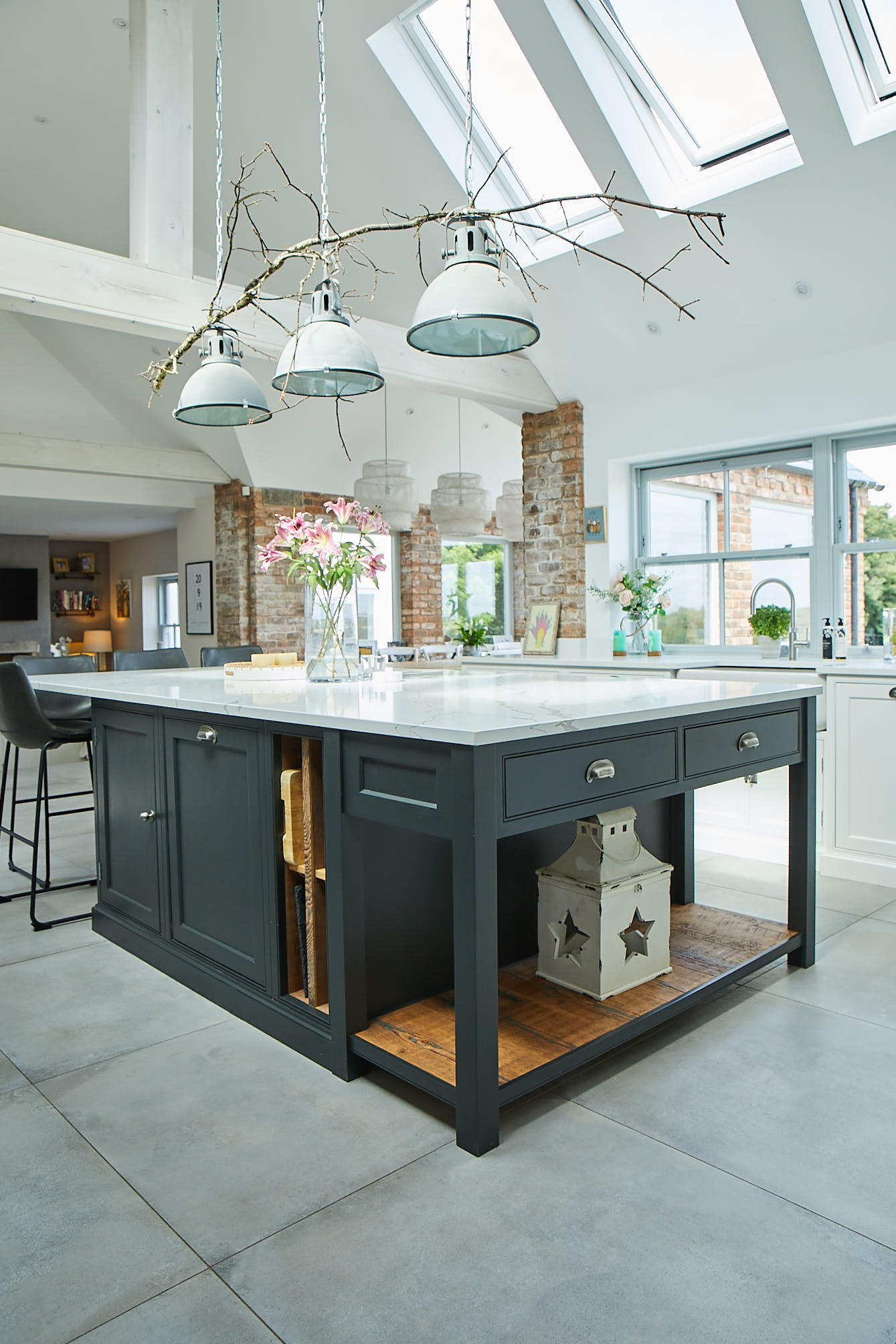 Industrial pendant lights hand above bespoke kitchen island with pot board end