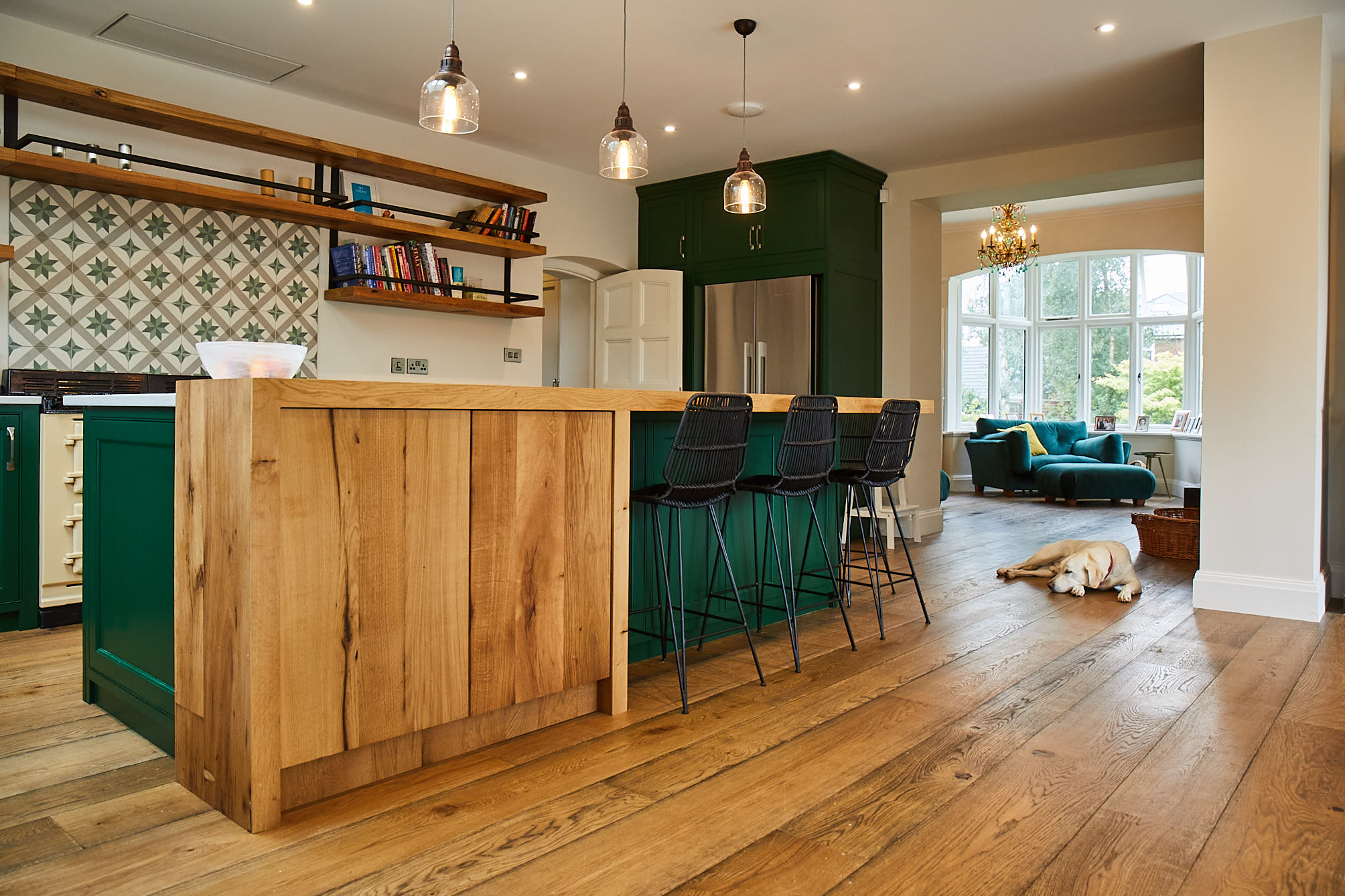 Dog sleeping in bespoke kitchen with green cabinets and oak breakfast bar