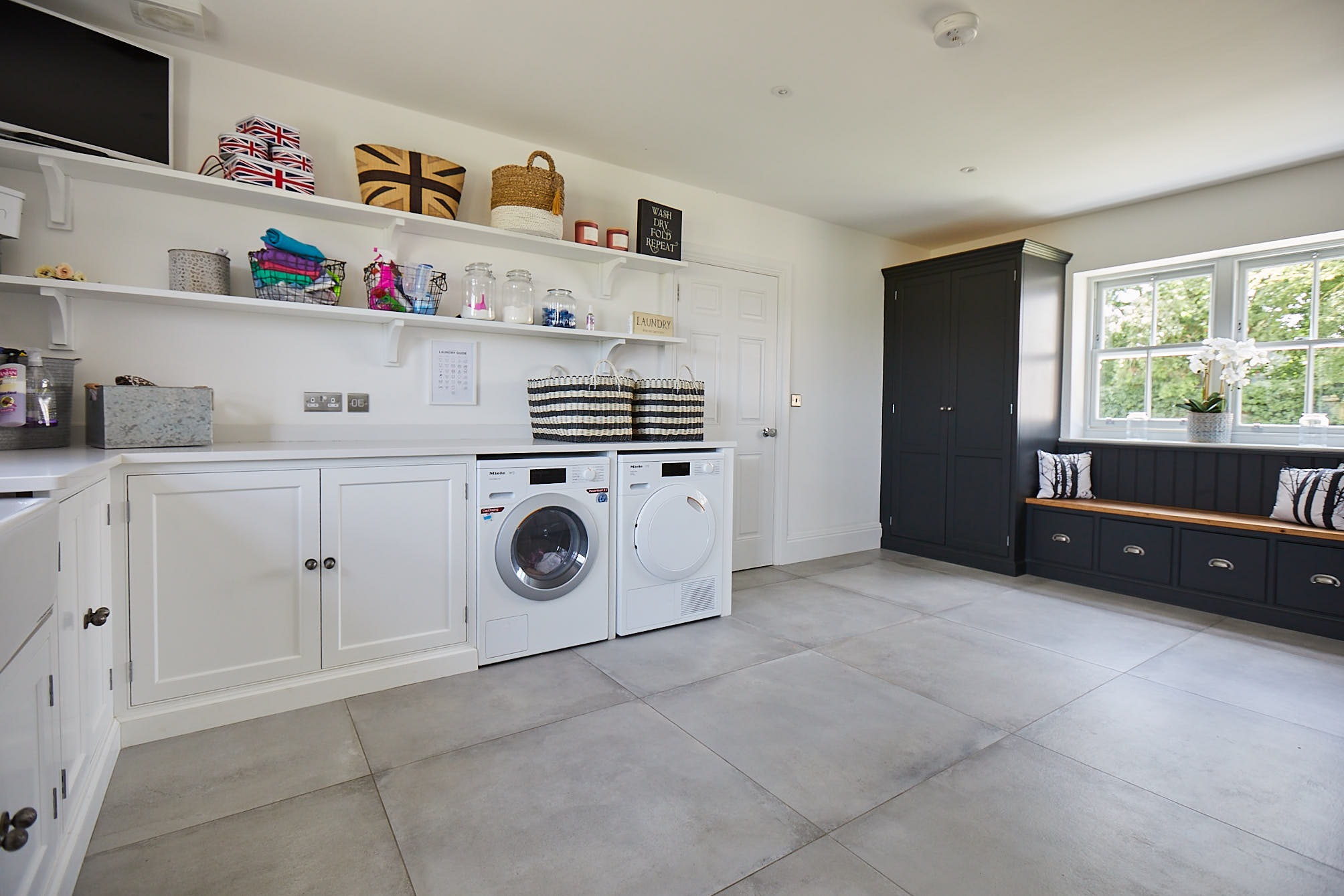 Contrasting white and black painted cabinets in utility room with freestanding washer and dryer