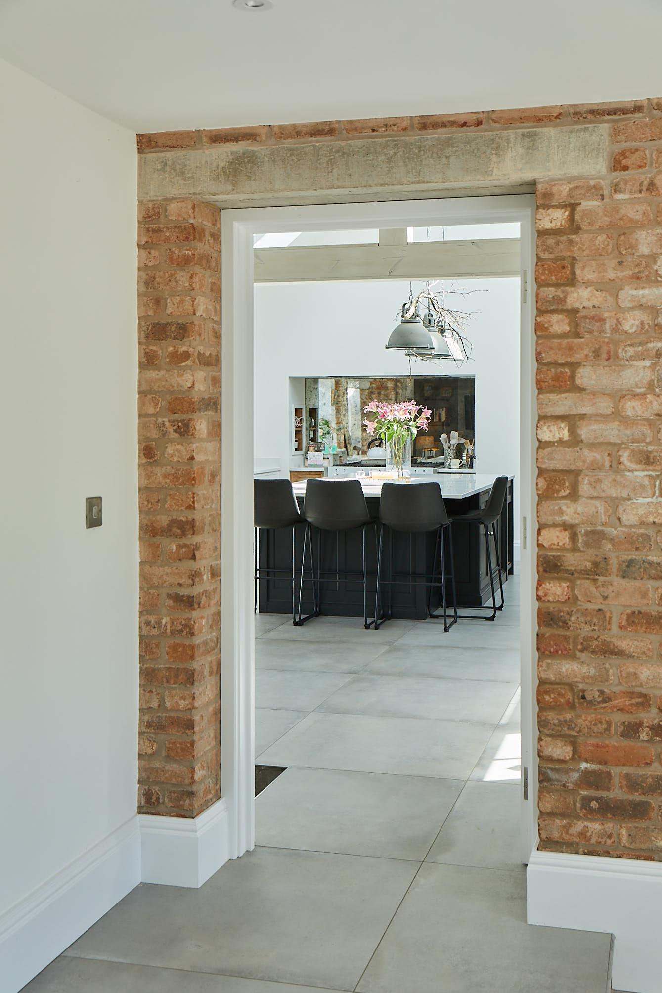 Exposed brick wall in kitchen leads to lamp black island