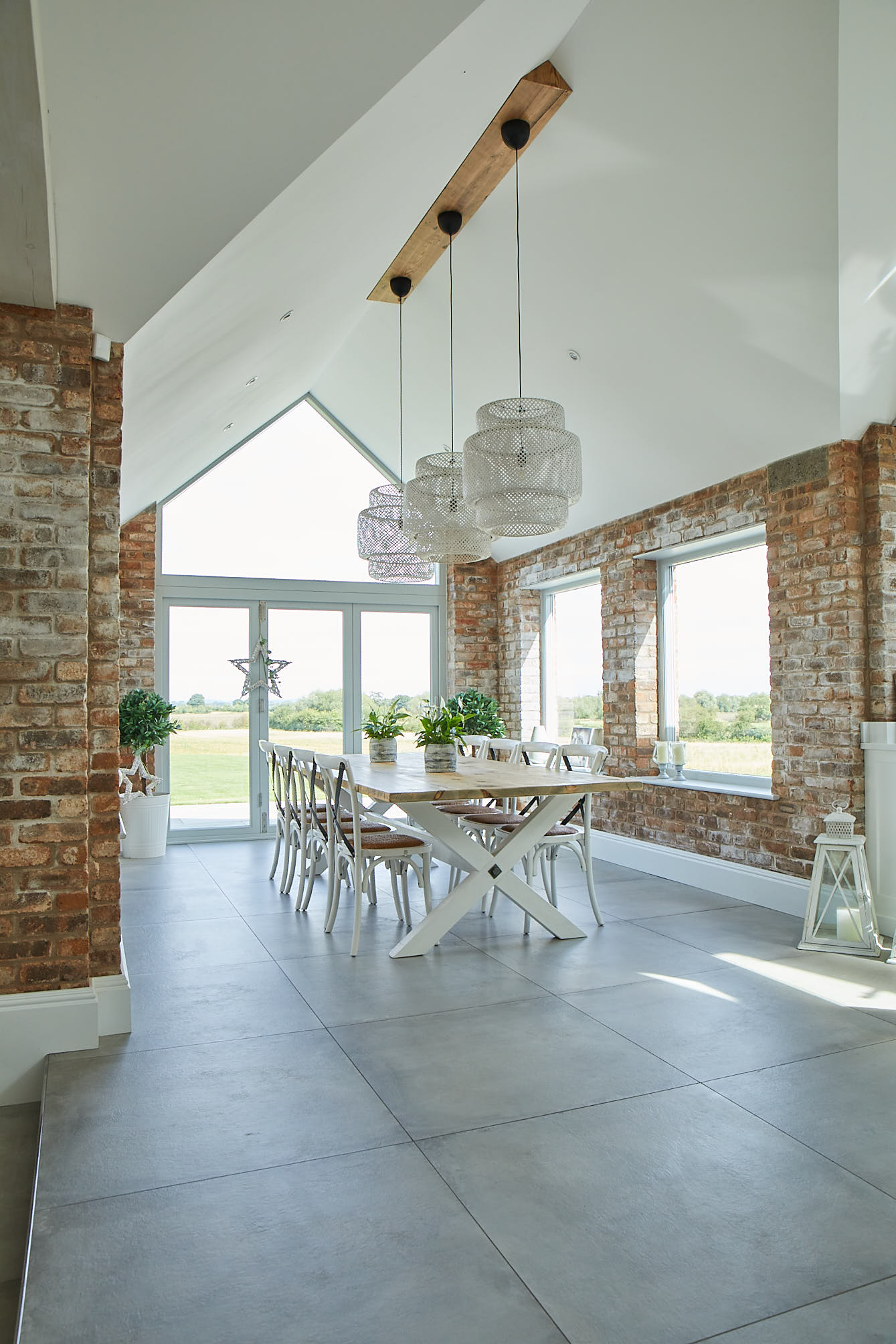 Large rattan pendant lights hang above x white painted table