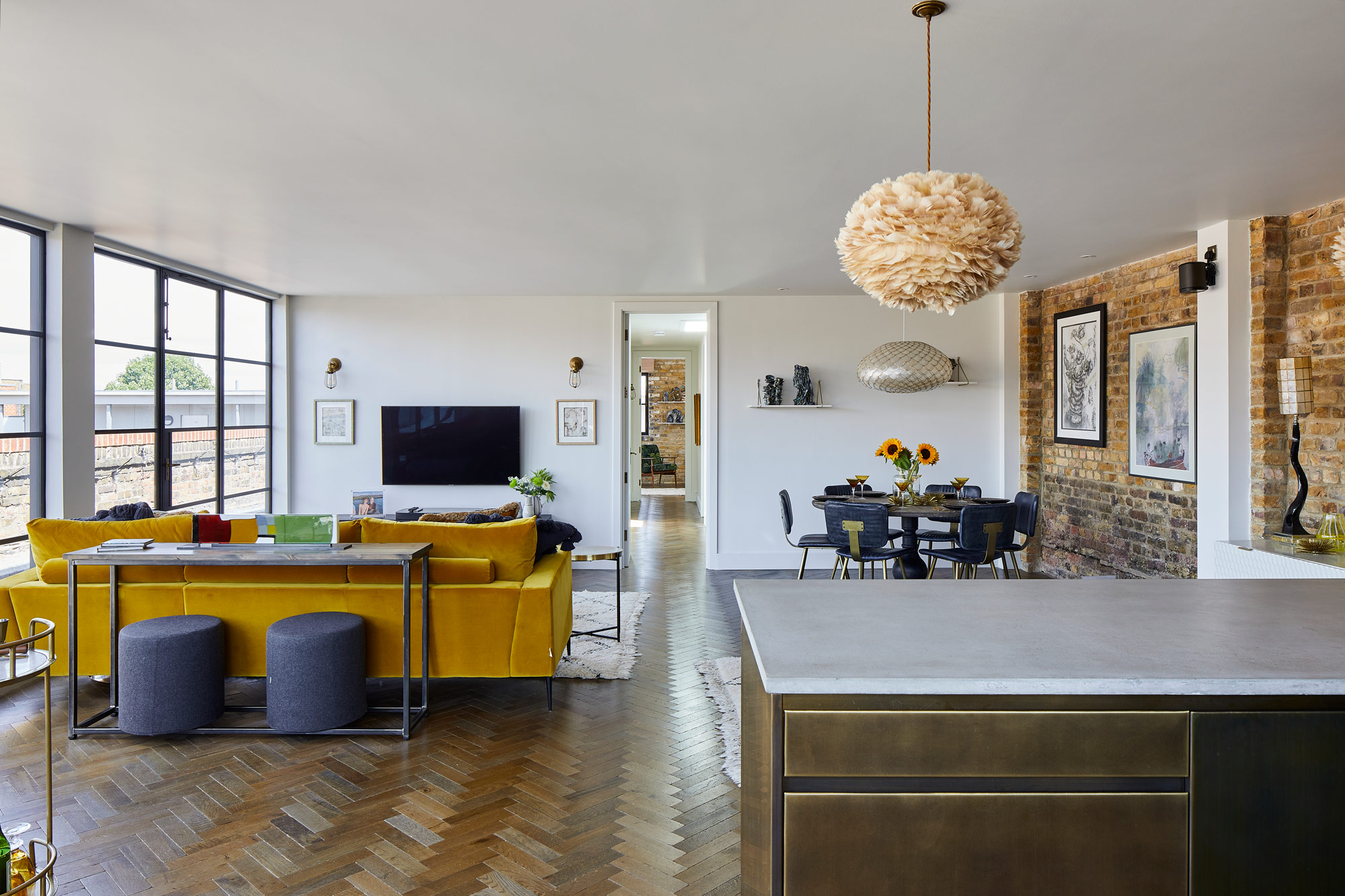 Open plan kitchen, living and dining area with metal kitchen and yellow sofa