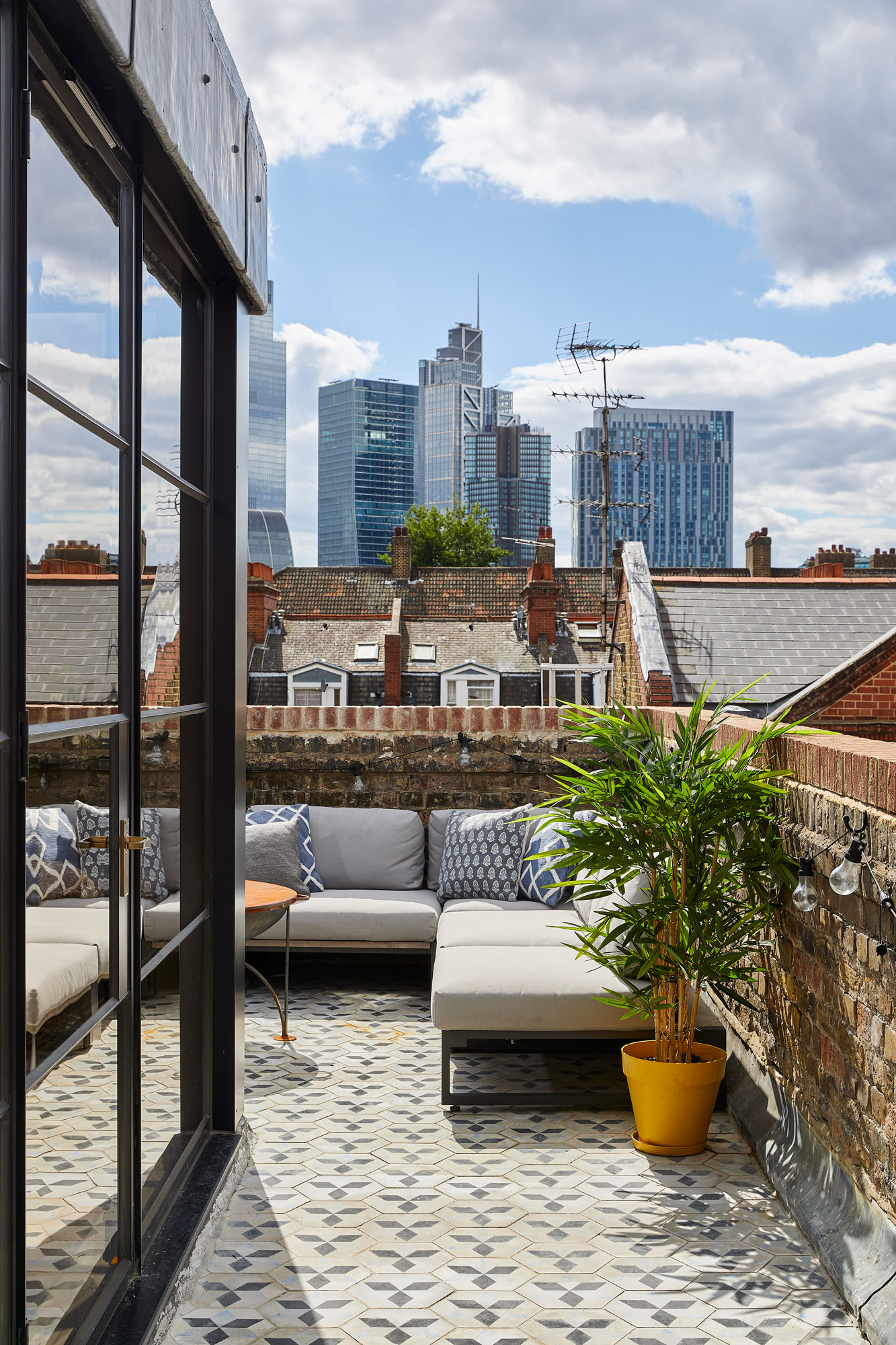 London rooftop apartment with upholstered outdoor furniture and reclaimed tiled patio