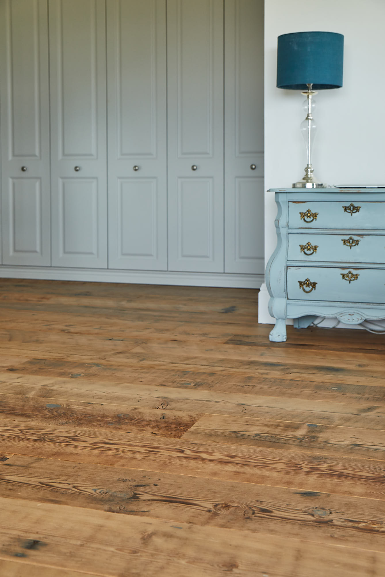 Original reclaimed flooring with blue bedside cabinet